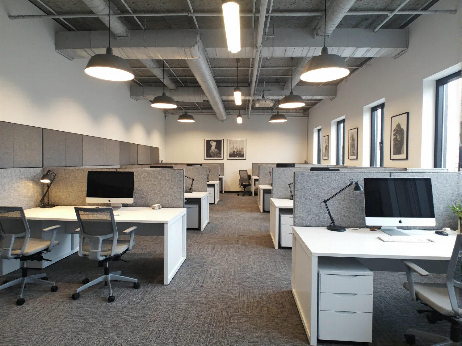 Minimalistyczna strefa relaksu w coworkingu z wygodną, szarą sofą i prostym stolikiem.